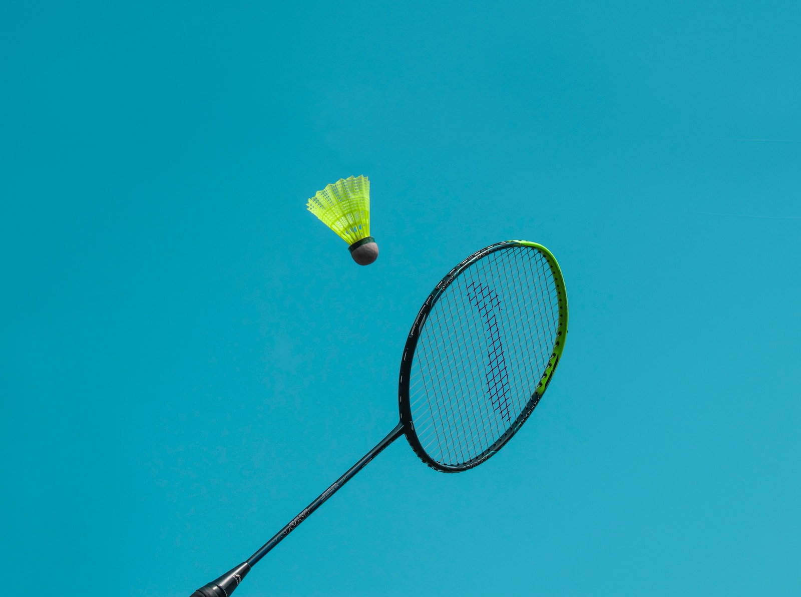 a badminton racket and a yellow frisbee flying in the air